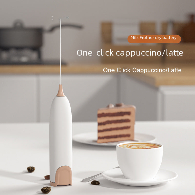 Bombom mini handheld milk frother with white and beige design next to cappuccino cup and cake slice